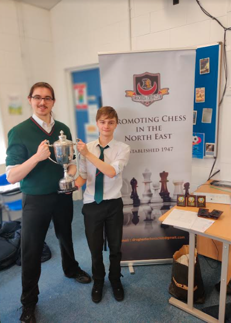 Two students holding a chess cup
